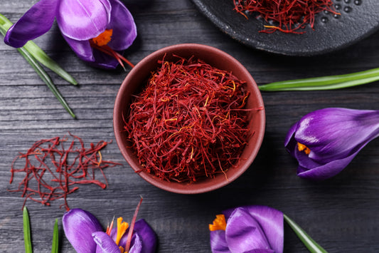 Dried saffron threads in a small bowl with crocus flowers